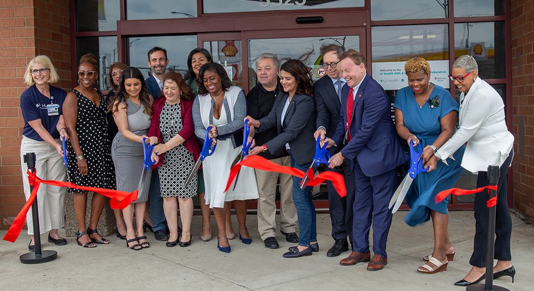 Health Collaborative leadership cutting a large red ribbon in front of the facility