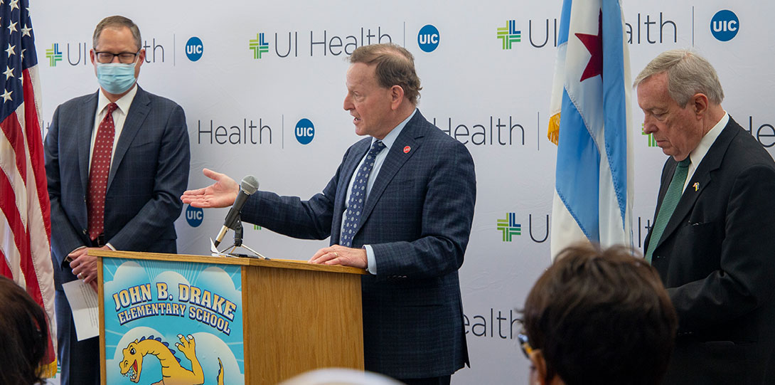 Dr. Robert A. Barish behind podium in front of UI Health banner