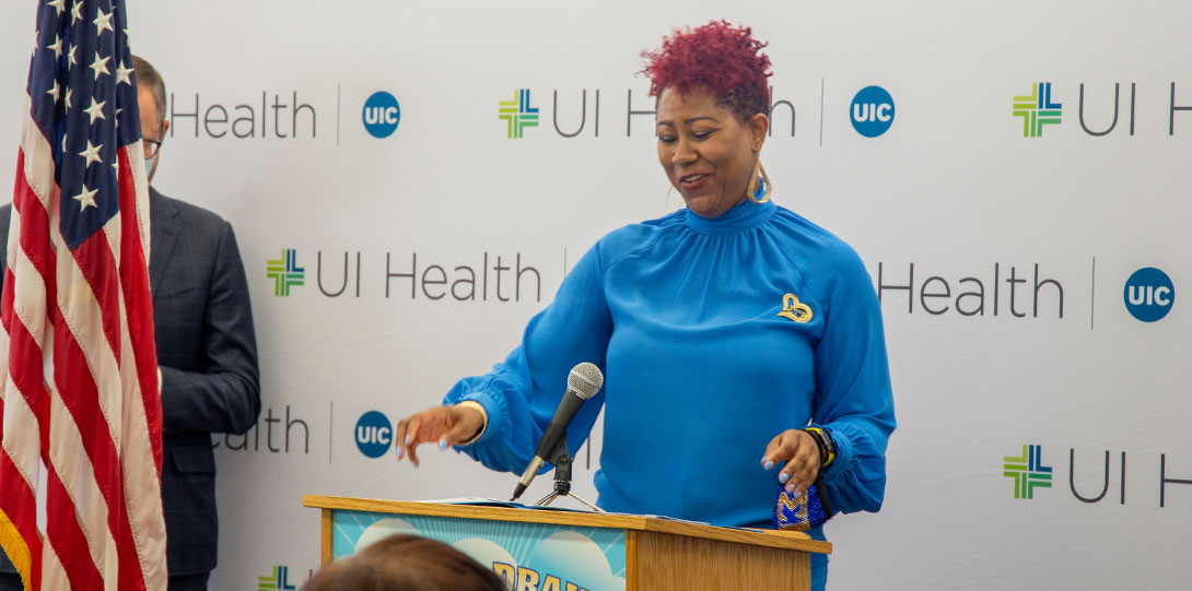 Drake Principal Golliday behind podium in front of UI Health banner