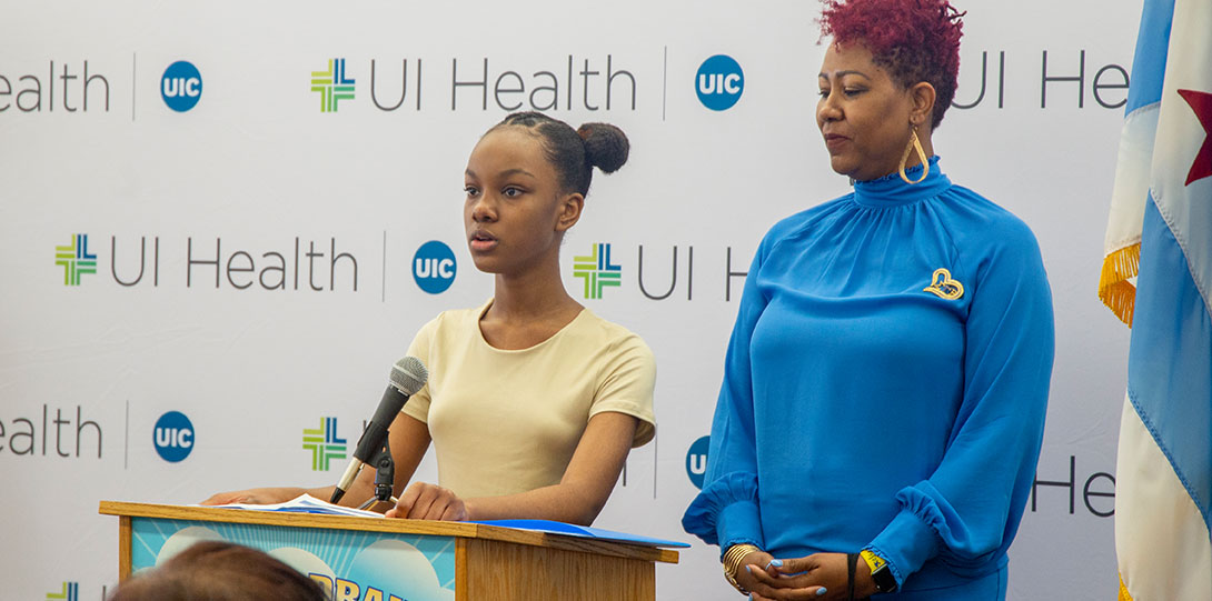 Female elementary school student behind podium in front of UI Health banner