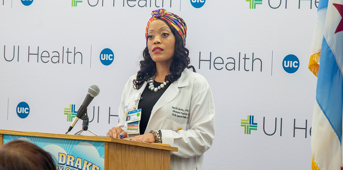 Aquila Shelby behind podium in front of UI Health banner