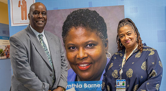 Henry Taylor and Angela Ellison posing in front of photo of Dr. Cynthia Barnes-Boyd at mile square school-based health center in John B. Drake Elementary School