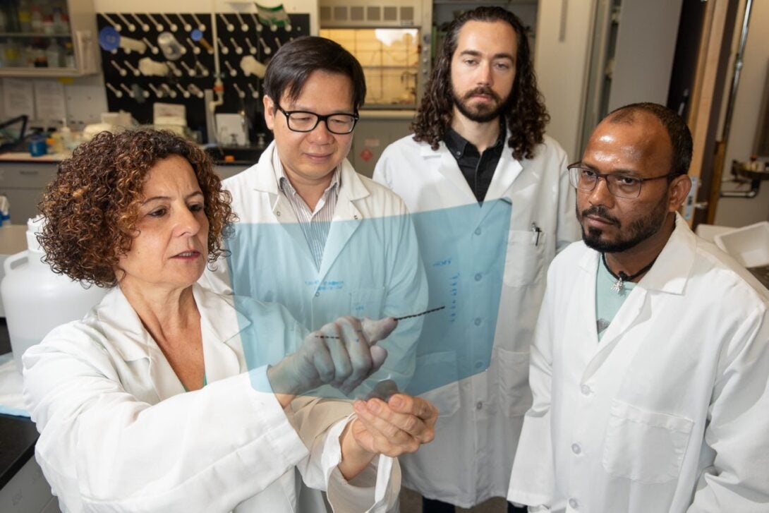 Dr. Lazarov and her team in white lab coats looking at transparency with data