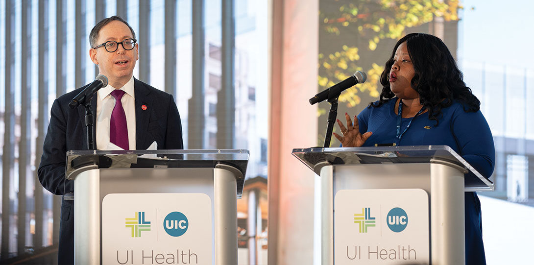Mark Rosenblatt and Lakesia Collins in formal attire, standing behind podiums with the UI Health logo on the front
