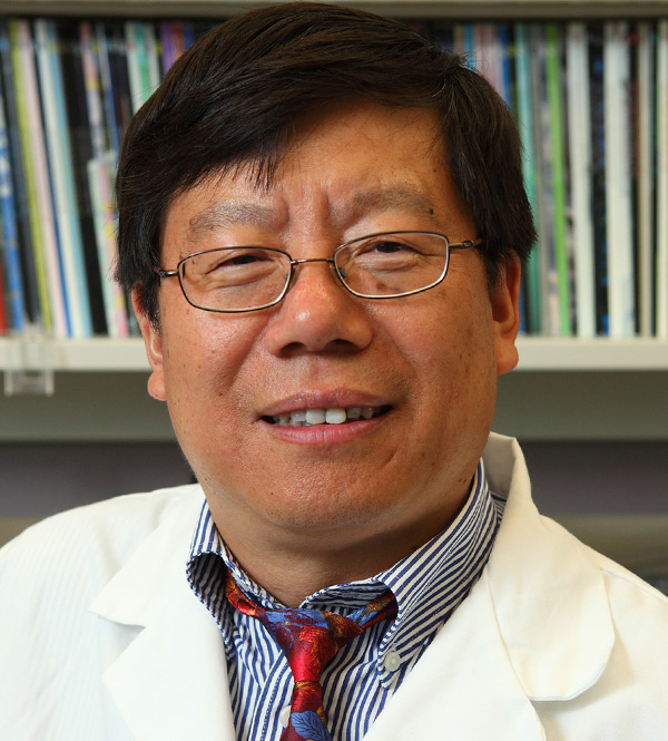 Dr. Lijun Rong in white lab coat posed in front of shelves of books