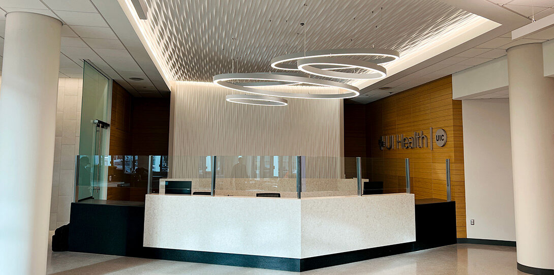 a modern white desk showing glass partitions with modern lighting fixtures above