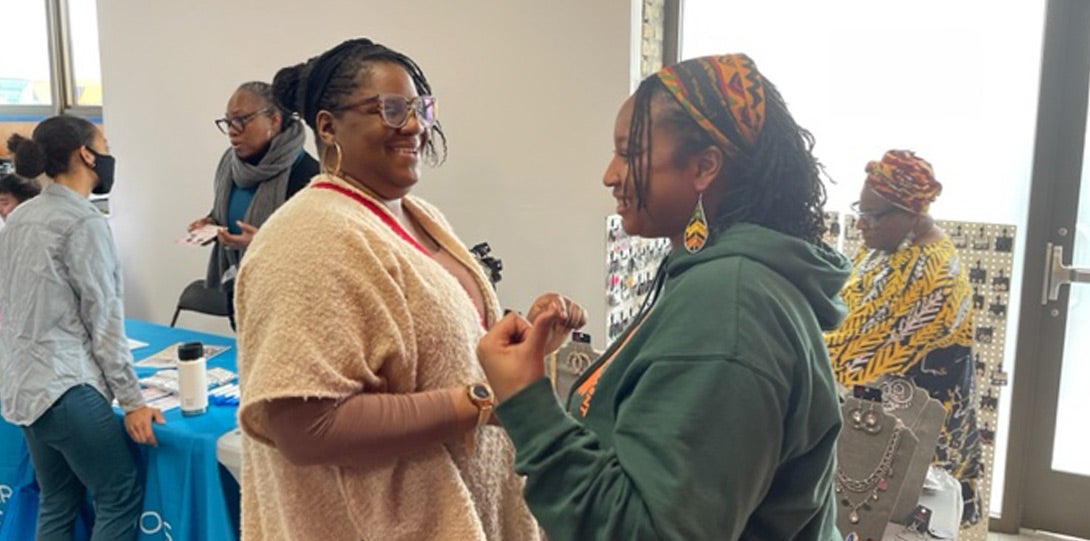 two African American women talking in front of a vendor booth