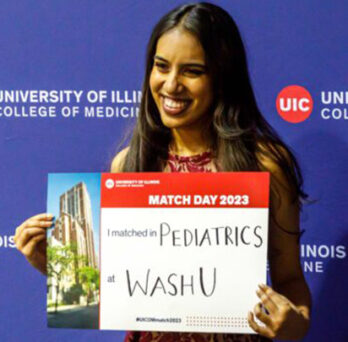 female student with brown hair holding a sign showing her residency match, in front of a backdrop with the College of Medicine logo 