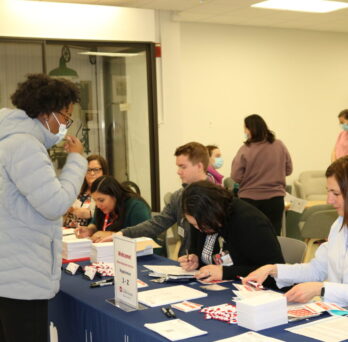 African-American woman standing at a table, collecting information about the program from staff 