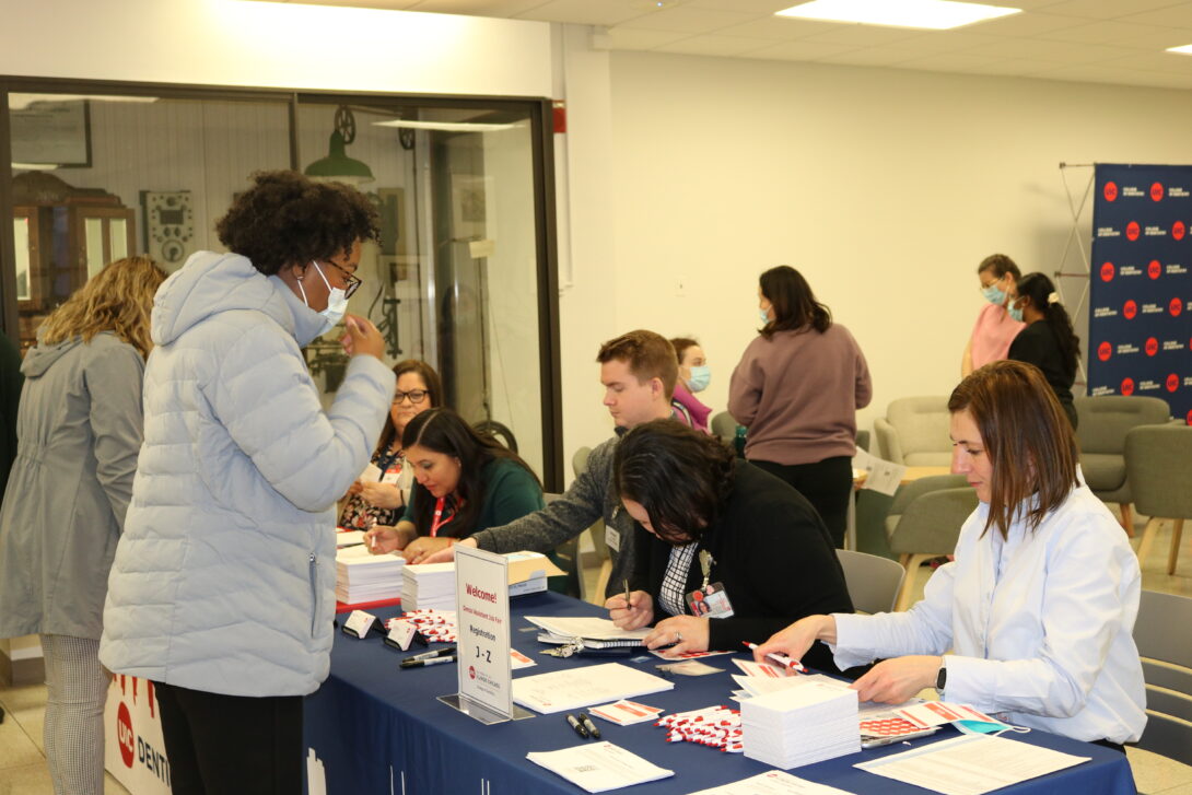 African-American woman standing at a table, collecting information about the program from staff