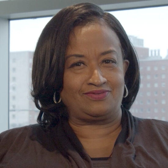 Angela Ellison smiling into the camera, with UIC west campus buildings in the background