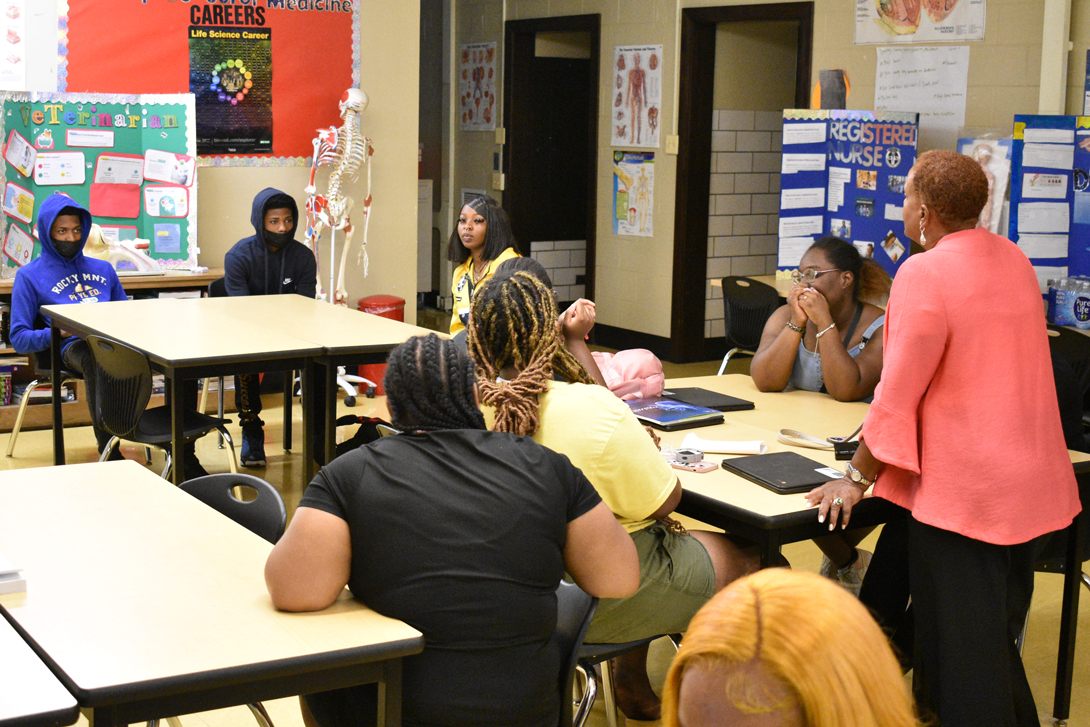 a classroom of African American students at the school, with an African American woman addressing the students