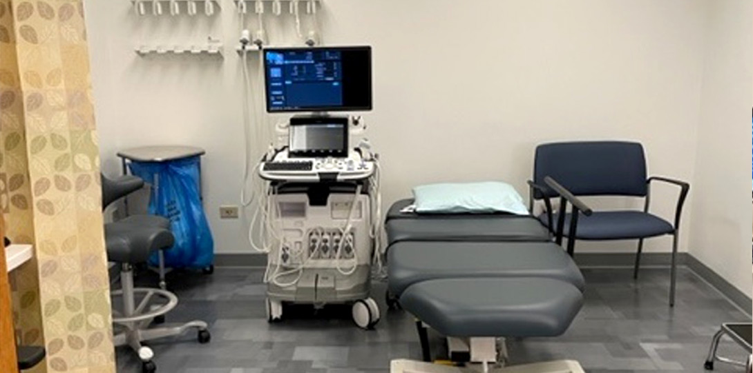 a clinic room with an exam table and an ultrasound machine