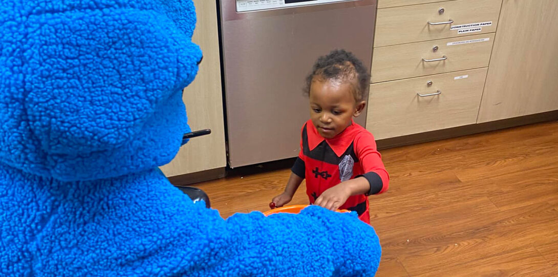 cookie monster giving candy to a small African American child