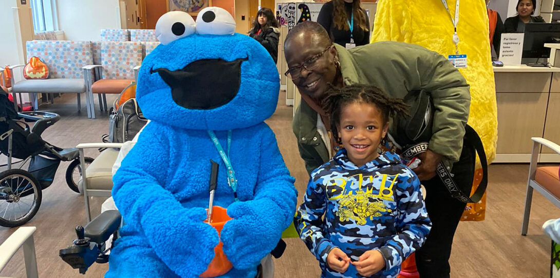 an African American family posing wiht Cookie Monster