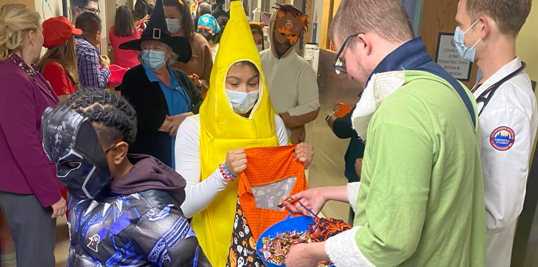 Many young people in costumes in the hallway of pediatrics receiving halloween treats