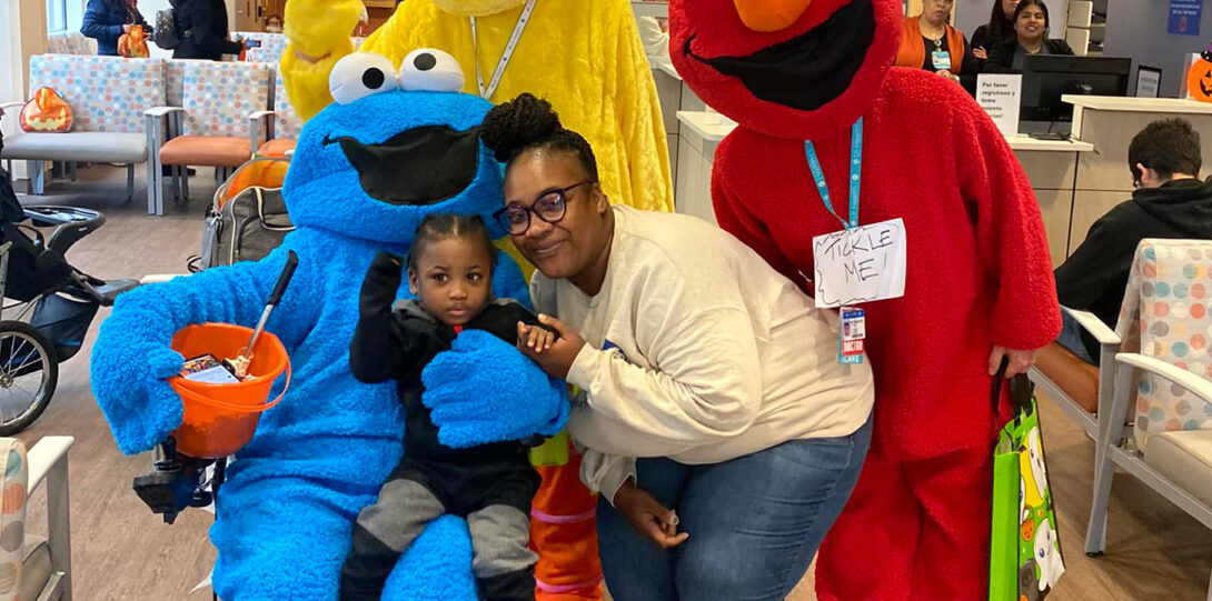 An African American family posing with Cookie Monster and Elmo