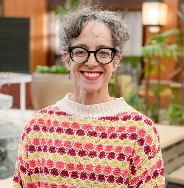 photo of Dr. Singer smiling and wearing glasses and a colorful sweater