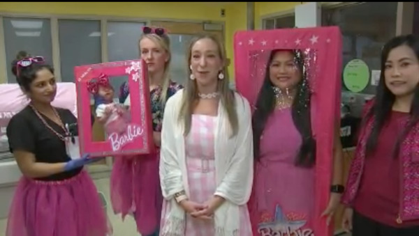 Sarah Davey being interviewed, standing with hospital staff in Barbie-related costumes