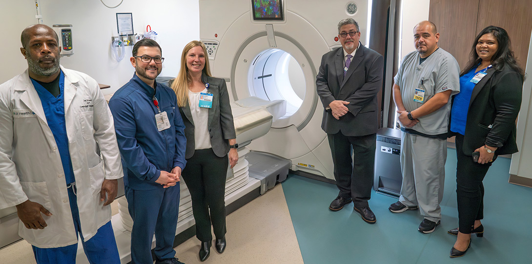 clinicians posing next to the new CT scanner