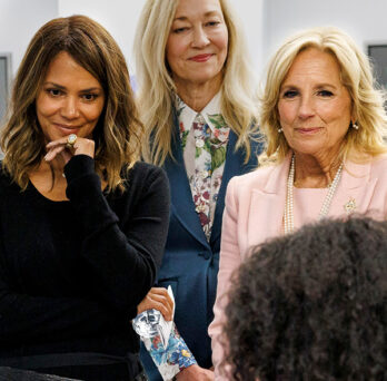 Dr. Jill Biden and Halle Berry standing side by side watching a research demonstration 
