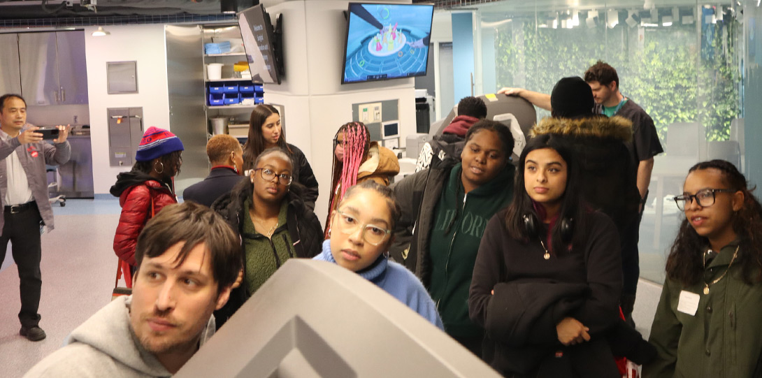 a large group of students turning to look at a digital display in the lab