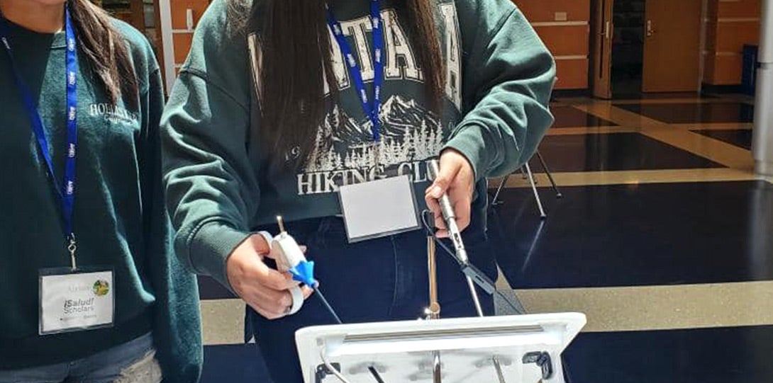 A female high school student working with a simulated non-invasive surgical device.