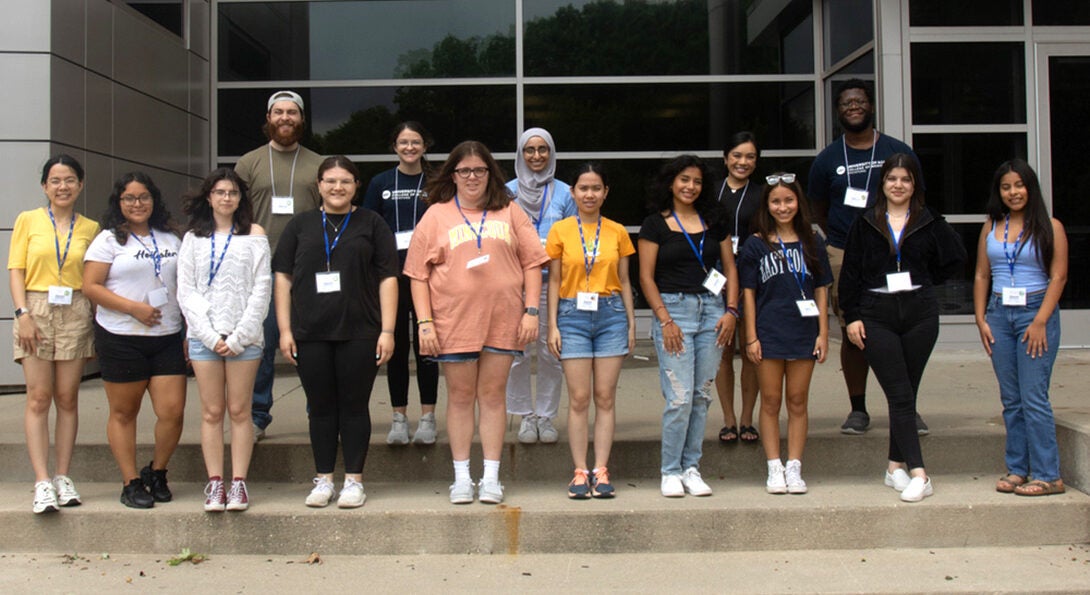 a diverse group of high school students and UIC medical students posing in a group on the steps of the main building on the UIC Rockford campus