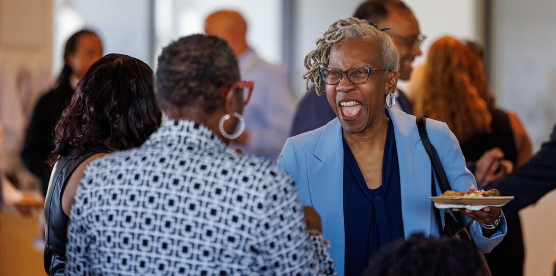 Two African American women smiling and laughing as they greet each other