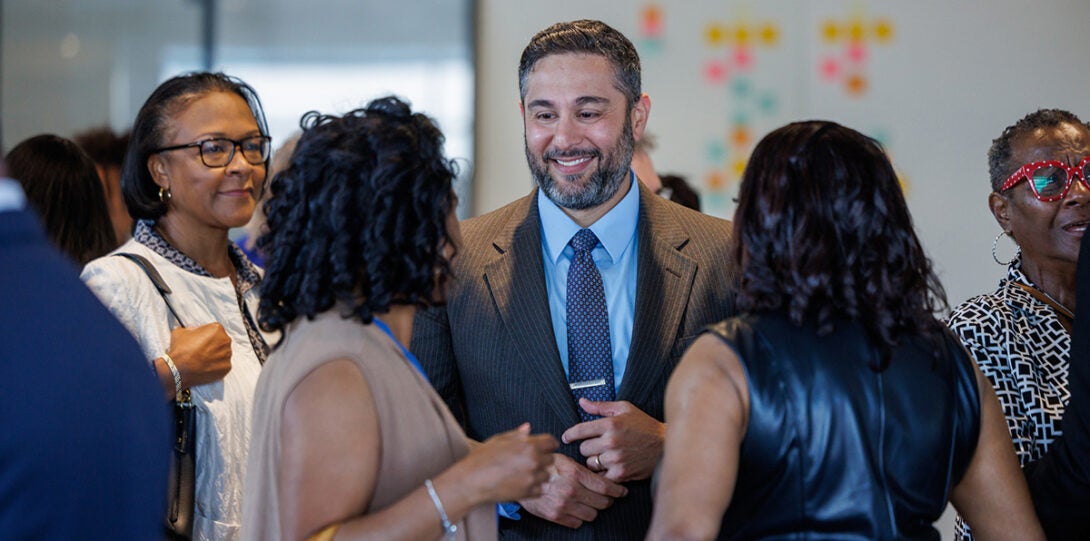 A group of three African American women and a man smiling as they converse