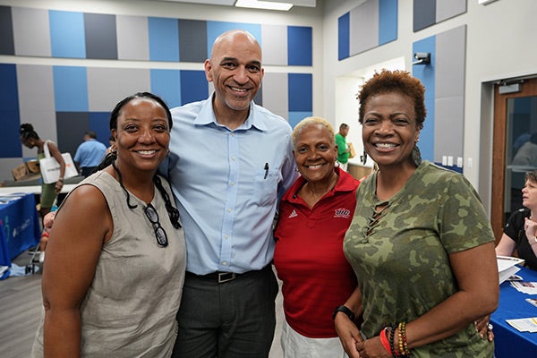 Four people in an event space, posing together and smiling