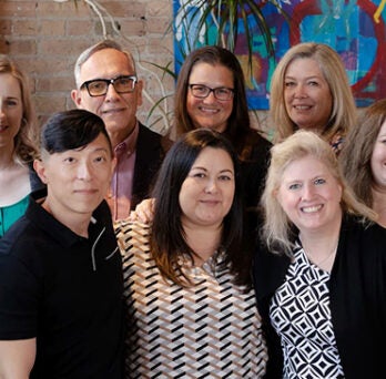 A group of 10 diverse individuals posing together in an office environment 